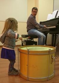 Luis al piano y una niña de corta edad tocando un tambor Luis al piano y una niña de corta edad tocando un tambor